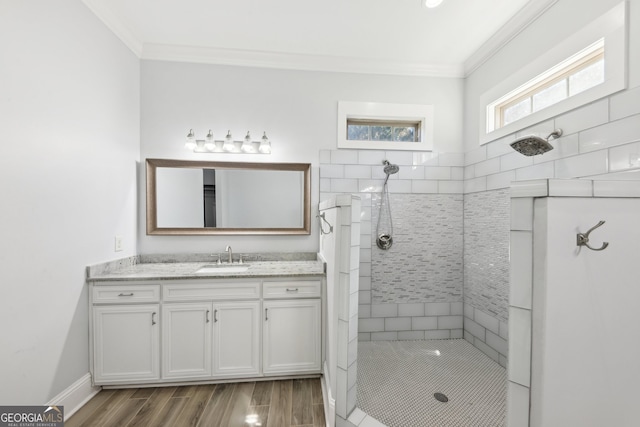 bathroom with vanity, wood-type flooring, tiled shower, and crown molding