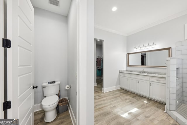 bathroom with wood-type flooring, crown molding, vanity, toilet, and a shower