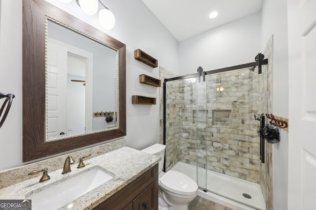 bathroom featuring toilet, vanity, and a shower with shower door