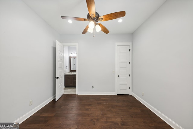 unfurnished bedroom featuring ensuite bath, dark wood-type flooring, and ceiling fan