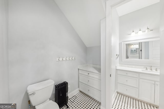 bathroom with toilet, radiator, vanity, and vaulted ceiling