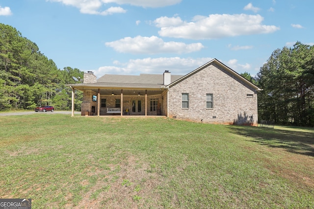 rear view of property featuring ceiling fan and a yard