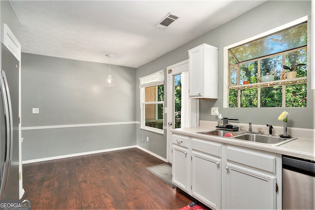 kitchen with hanging light fixtures, a textured ceiling, dark wood-type flooring, white cabinetry, and stainless steel appliances