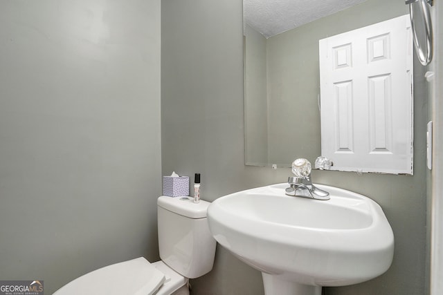 bathroom with a textured ceiling, sink, and toilet