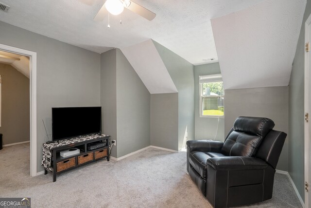 sitting room with ceiling fan, a textured ceiling, lofted ceiling, and light carpet