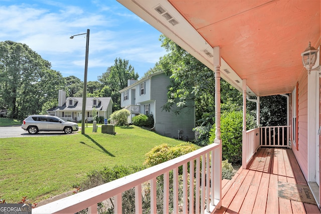 wooden deck featuring a porch and a yard