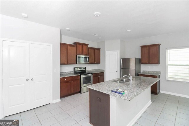 kitchen with appliances with stainless steel finishes, sink, light tile patterned floors, and light stone counters