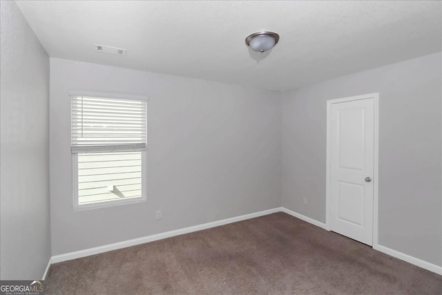 unfurnished room featuring dark colored carpet and a wealth of natural light