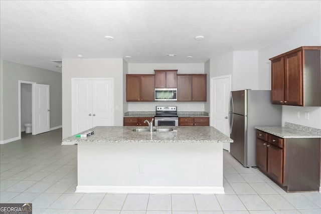 kitchen with a center island with sink, appliances with stainless steel finishes, and light tile patterned flooring