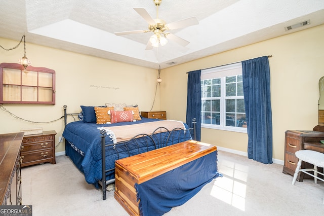 bedroom with light carpet, a tray ceiling, ceiling fan, and a textured ceiling