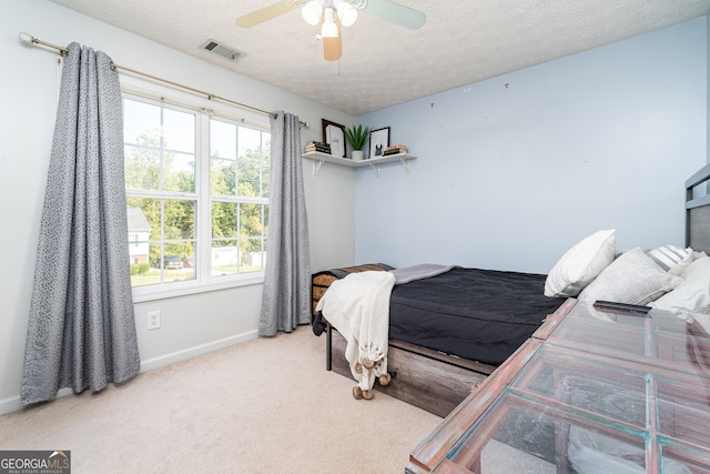 bedroom with ceiling fan, a textured ceiling, and light carpet