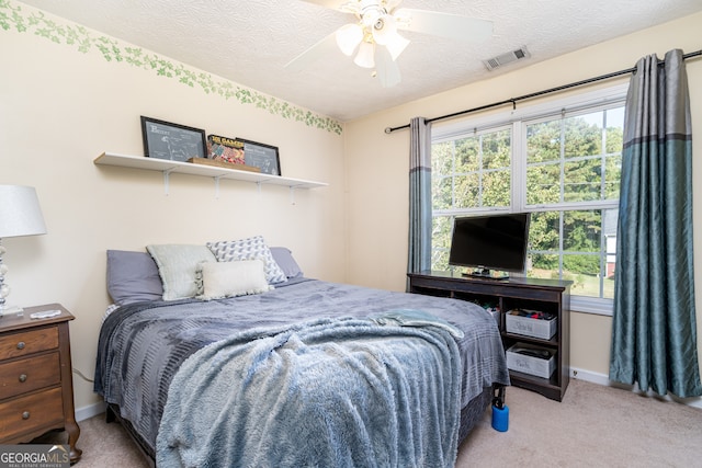 carpeted bedroom featuring ceiling fan, multiple windows, and a textured ceiling