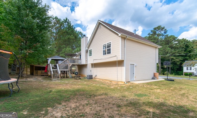 view of side of home featuring central AC unit, a trampoline, a deck, and a yard