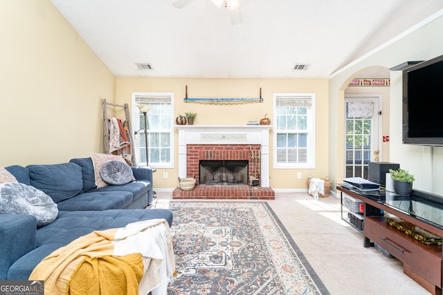 living room featuring ceiling fan, light colored carpet, and a brick fireplace