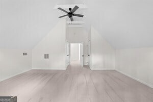 interior space with ceiling fan, light colored carpet, and vaulted ceiling