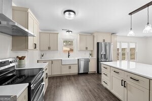 kitchen featuring kitchen peninsula, dark hardwood / wood-style flooring, pendant lighting, stainless steel appliances, and wall chimney range hood