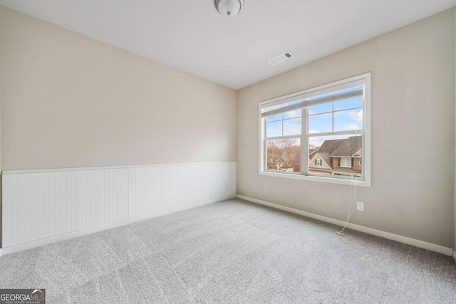 carpeted spare room with visible vents and baseboards