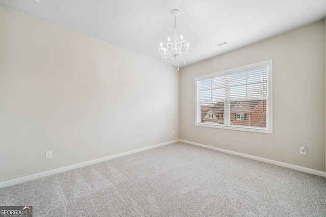 spare room featuring an inviting chandelier, carpet, visible vents, and baseboards