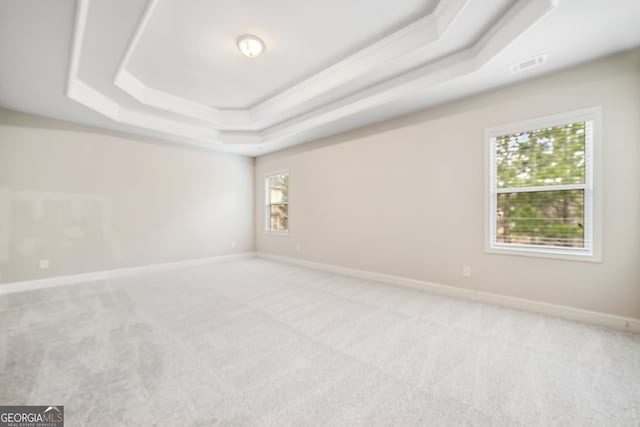 unfurnished room with visible vents, a raised ceiling, light colored carpet, and baseboards