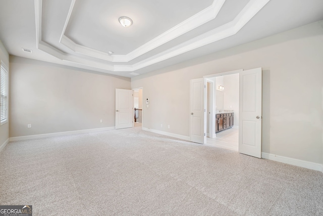 unfurnished bedroom featuring visible vents, light colored carpet, baseboards, and a tray ceiling