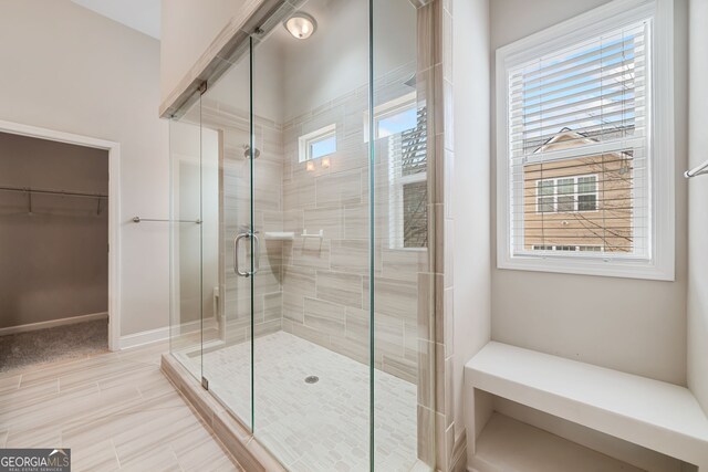 bathroom with a spacious closet and a stall shower