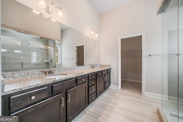 bathroom with double vanity, a shower stall, a spacious closet, and a sink