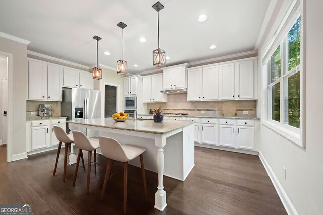 kitchen with ornamental molding, backsplash, dark wood finished floors, appliances with stainless steel finishes, and white cabinets