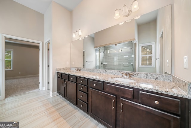 bathroom with double vanity, a stall shower, baseboards, and a sink