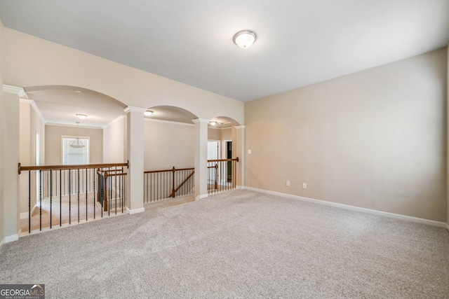 unfurnished room with carpet flooring, baseboards, and ornate columns