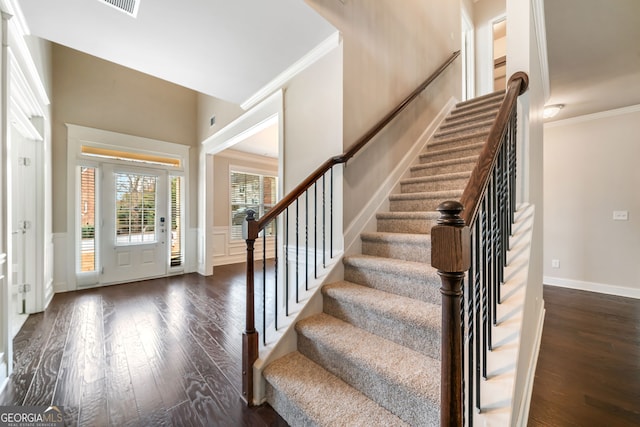 entryway with a decorative wall, dark wood-style floors, wainscoting, and ornamental molding