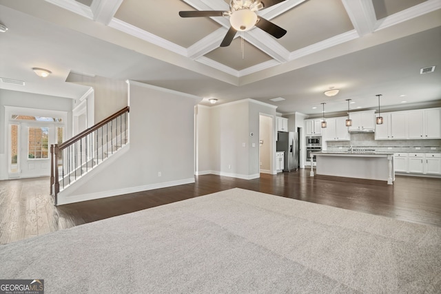 unfurnished living room featuring visible vents, ceiling fan, dark wood finished floors, stairs, and coffered ceiling