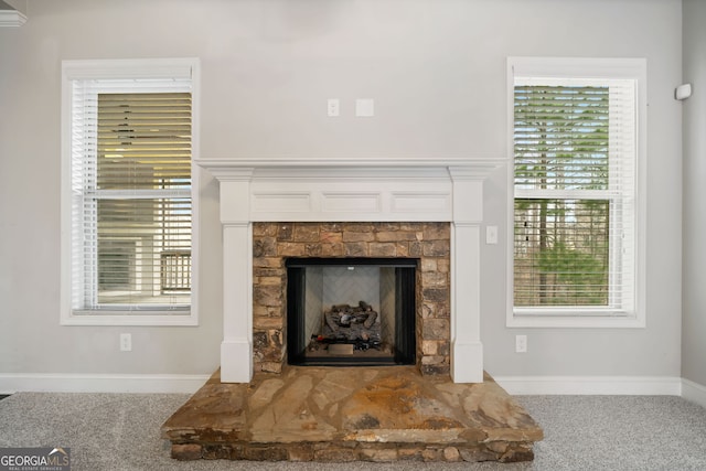 details featuring baseboards, carpet floors, and a fireplace with raised hearth