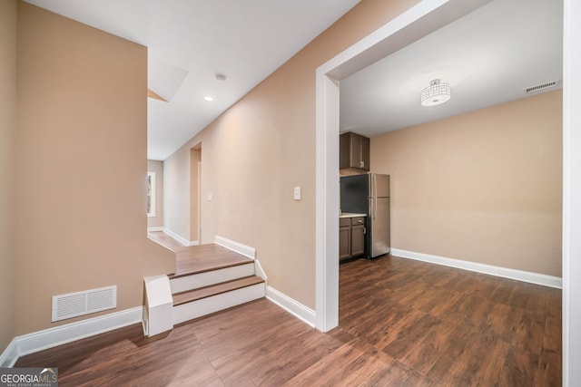 corridor featuring dark wood-type flooring, baseboards, and visible vents