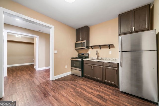 kitchen featuring dark wood-style floors, baseboards, a sink, stainless steel appliances, and dark brown cabinetry