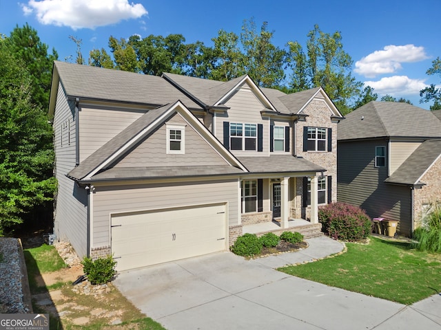 craftsman-style home featuring a front yard, covered porch, concrete driveway, a garage, and brick siding
