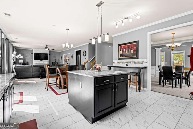 kitchen featuring hanging light fixtures, ceiling fan with notable chandelier, ornamental molding, and a center island