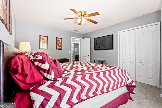 bedroom with ceiling fan, light colored carpet, and a closet