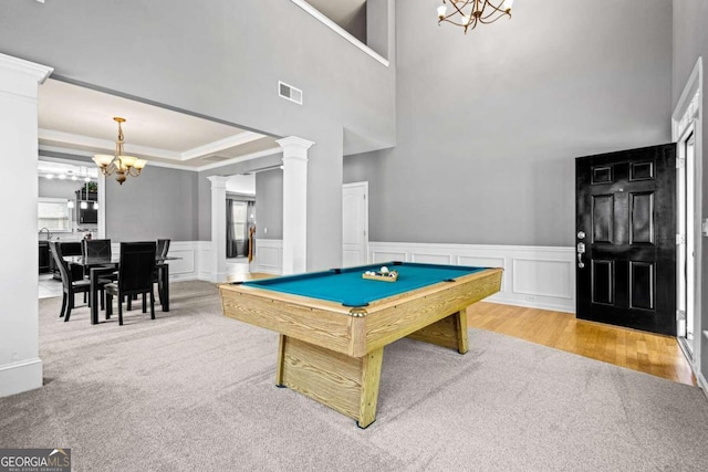 carpeted dining room with decorative columns, a tray ceiling, and an inviting chandelier