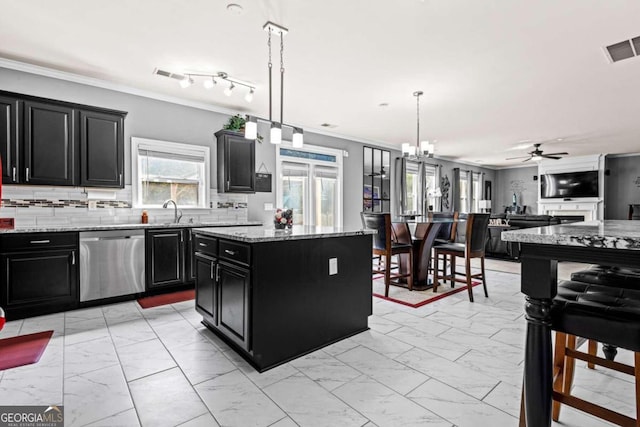 kitchen with appliances with stainless steel finishes, backsplash, light stone countertops, a center island, and decorative light fixtures