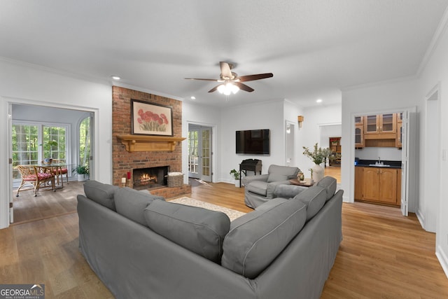 living room featuring sink, ornamental molding, a brick fireplace, and wood-type flooring