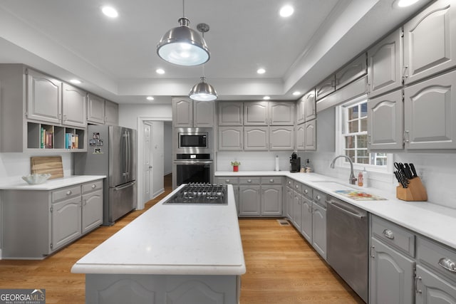 kitchen with gray cabinets, a kitchen island, stainless steel appliances, and decorative light fixtures