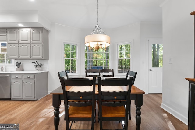 dining space with ornamental molding, an inviting chandelier, and light hardwood / wood-style floors