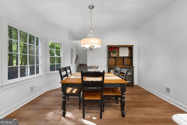 dining area featuring ornamental molding, dark wood-type flooring, and an inviting chandelier