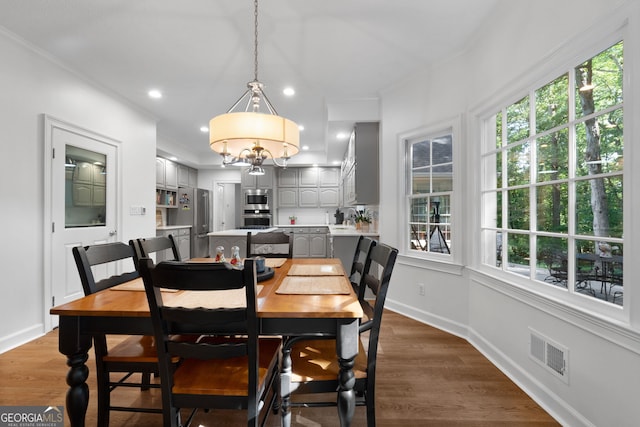 dining space with ornamental molding and dark wood-type flooring