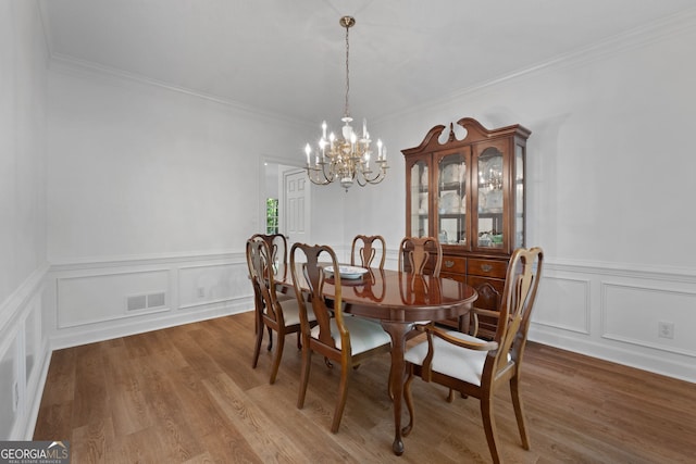 dining room with crown molding, a chandelier, and wood-type flooring