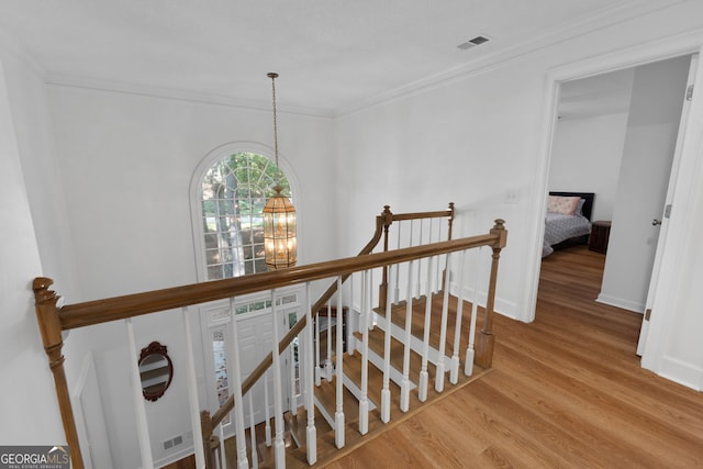 stairs featuring hardwood / wood-style flooring, a chandelier, and crown molding