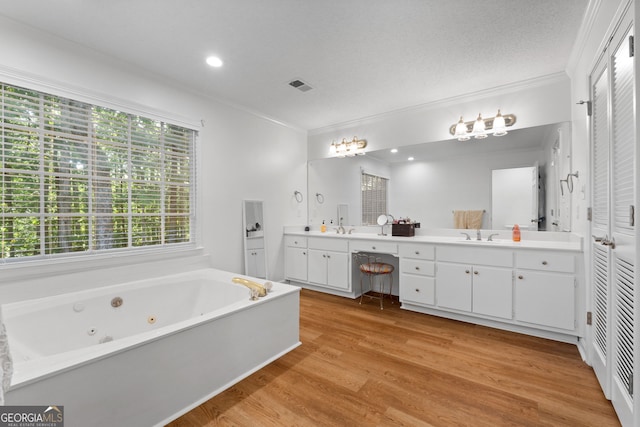 bathroom featuring a textured ceiling, crown molding, a bathing tub, hardwood / wood-style floors, and vanity