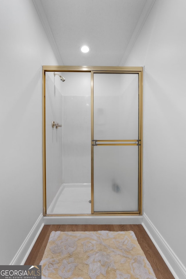 bathroom with hardwood / wood-style floors, an enclosed shower, and ornamental molding