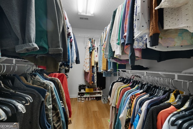 walk in closet with light hardwood / wood-style floors