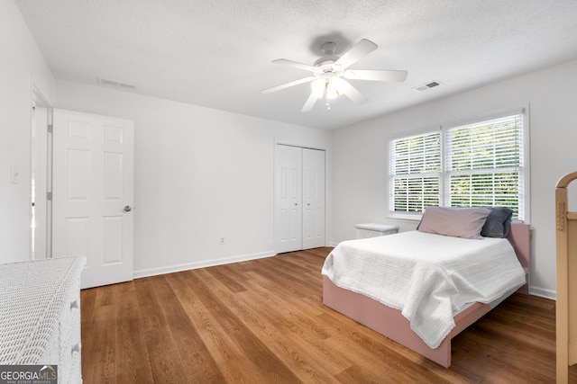 bedroom with a textured ceiling, a closet, ceiling fan, and light hardwood / wood-style flooring